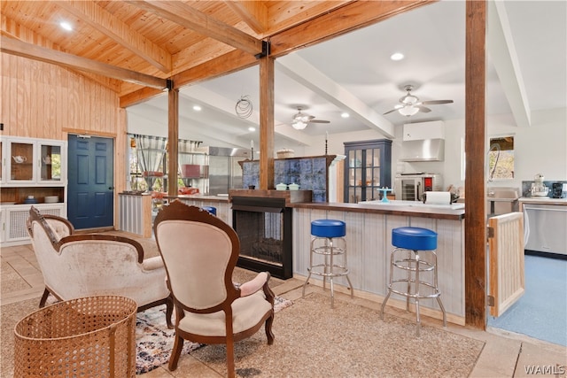 kitchen with wooden ceiling, lofted ceiling with beams, a kitchen breakfast bar, range hood, and a healthy amount of sunlight