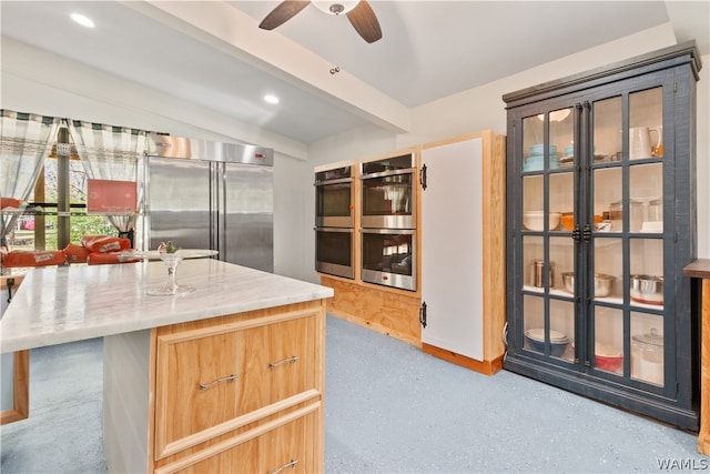 kitchen featuring ceiling fan, a kitchen island, beam ceiling, and appliances with stainless steel finishes