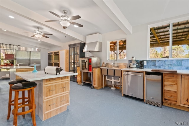 kitchen featuring ceiling fan, a breakfast bar area, decorative backsplash, a kitchen island, and appliances with stainless steel finishes