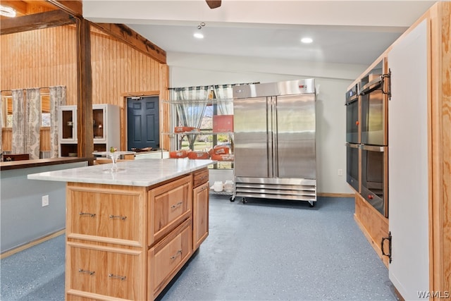 kitchen featuring vaulted ceiling, double oven, a kitchen island, and high end fridge