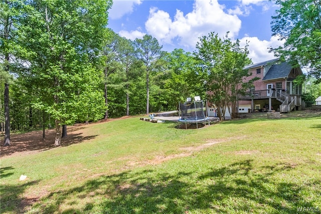 view of yard featuring a wooden deck and a trampoline