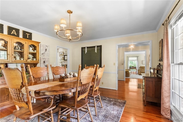 dining space with ornamental molding, light hardwood / wood-style floors, and an inviting chandelier