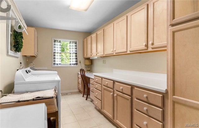 laundry area featuring washer and clothes dryer, cabinets, and light tile patterned floors