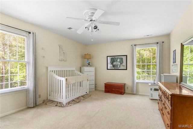 carpeted bedroom with a nursery area and ceiling fan