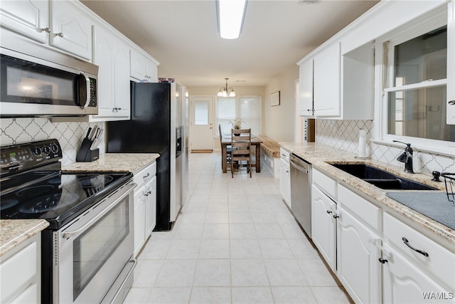 kitchen featuring light stone counters, sink, stainless steel appliances, and white cabinets