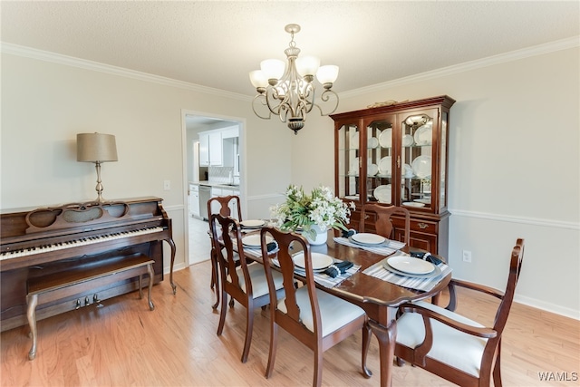 dining space with a notable chandelier, crown molding, and light hardwood / wood-style flooring