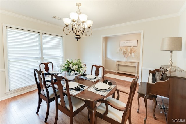 dining space with hardwood / wood-style flooring, crown molding, and a chandelier