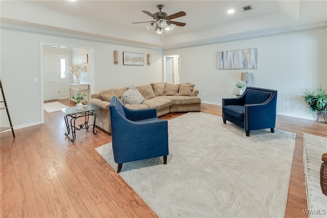 living room with ceiling fan, light hardwood / wood-style floors, and a tray ceiling