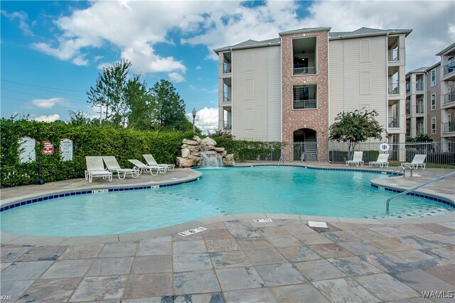 view of swimming pool featuring pool water feature and a patio