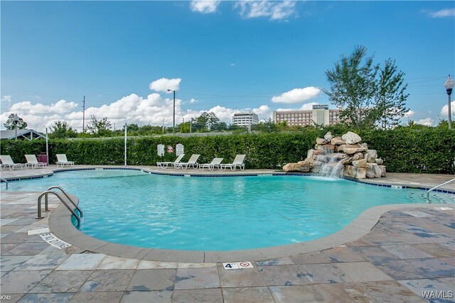 view of swimming pool featuring pool water feature and a patio area