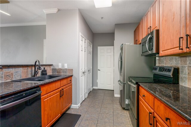 kitchen with sink, stainless steel appliances, tasteful backsplash, crown molding, and dark stone counters