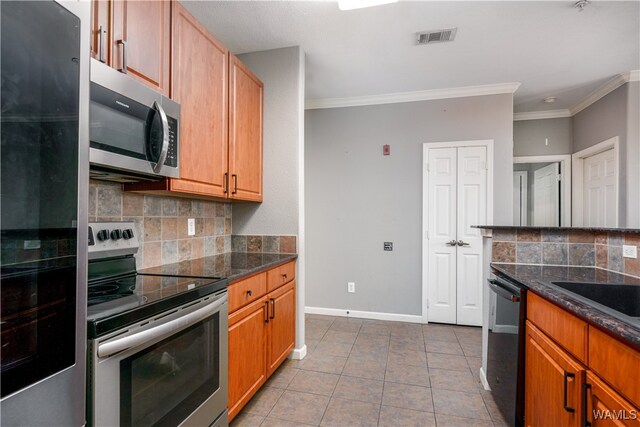 kitchen with appliances with stainless steel finishes, backsplash, ornamental molding, light tile patterned floors, and dark stone countertops