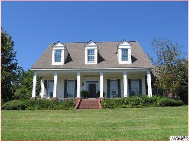 new england style home featuring covered porch and a front yard