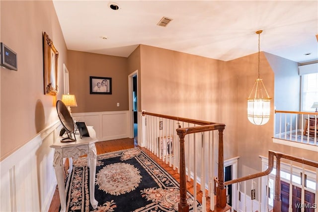 hallway featuring wood-type flooring and a notable chandelier