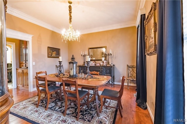 dining area with light wood-type flooring, an inviting chandelier, and crown molding