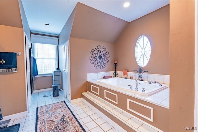 bathroom with a washtub, lofted ceiling, a healthy amount of sunlight, and tile patterned flooring