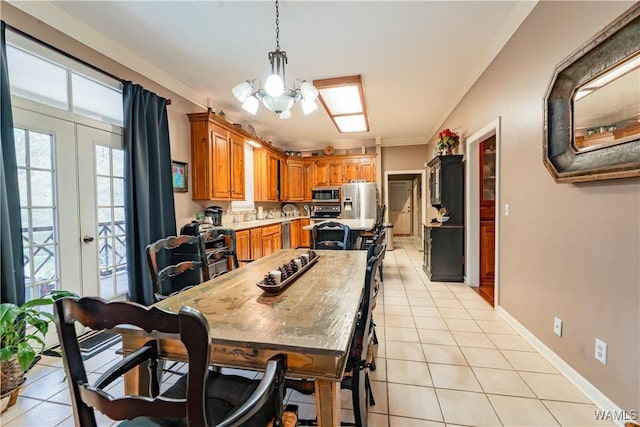 tiled dining room with french doors, ornamental molding, and a chandelier