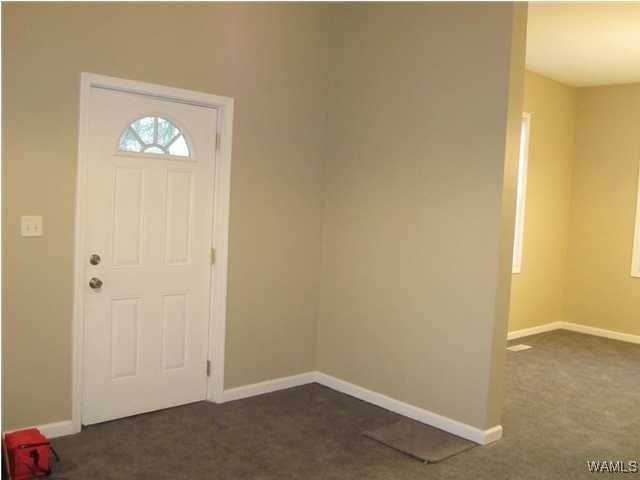 foyer with dark colored carpet and baseboards