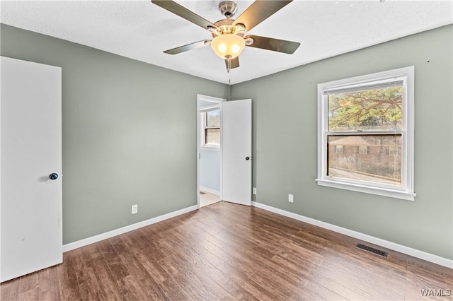 unfurnished bedroom featuring ceiling fan, visible vents, baseboards, and wood finished floors