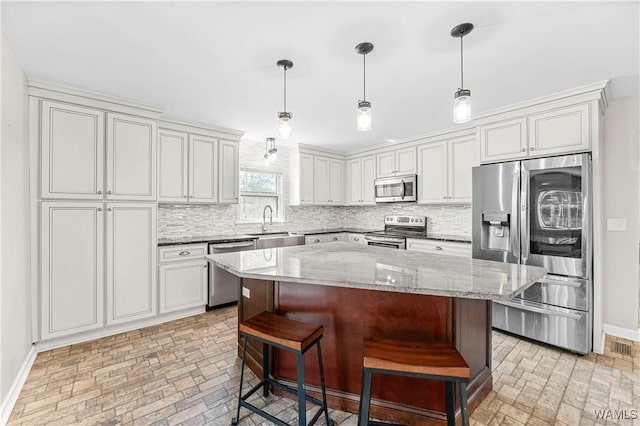 kitchen featuring a breakfast bar, light stone counters, tasteful backsplash, appliances with stainless steel finishes, and baseboards