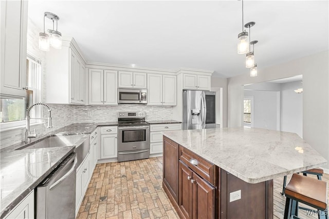 kitchen with tasteful backsplash, pendant lighting, appliances with stainless steel finishes, white cabinets, and a sink