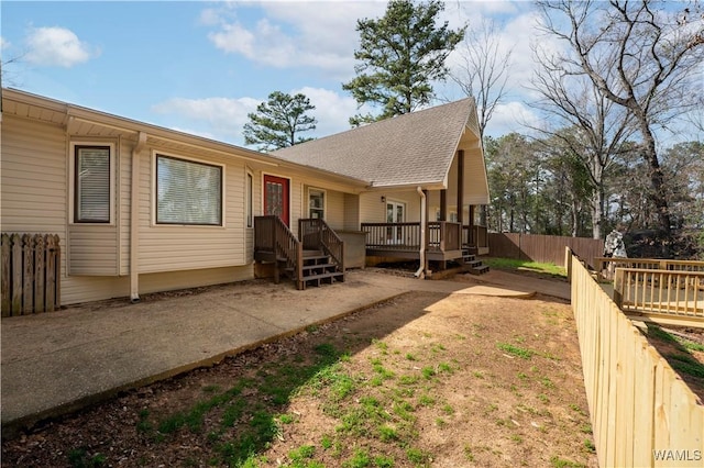 exterior space with roof with shingles, a deck, and fence