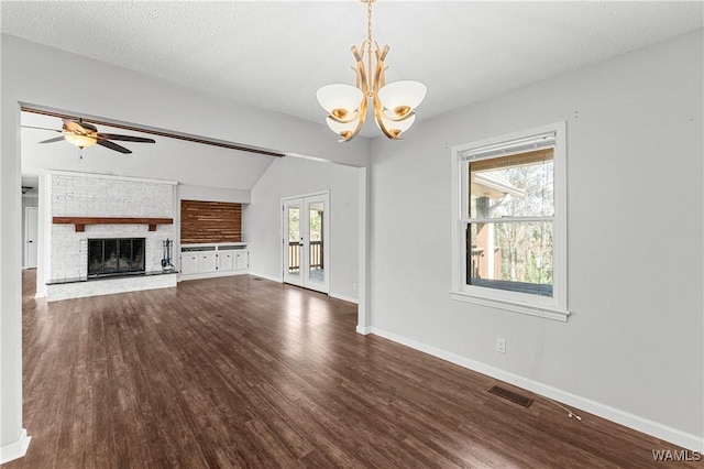 unfurnished living room featuring visible vents, baseboards, ceiling fan with notable chandelier, a fireplace, and wood finished floors