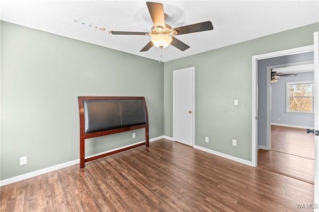 unfurnished bedroom featuring a ceiling fan, wood finished floors, and baseboards