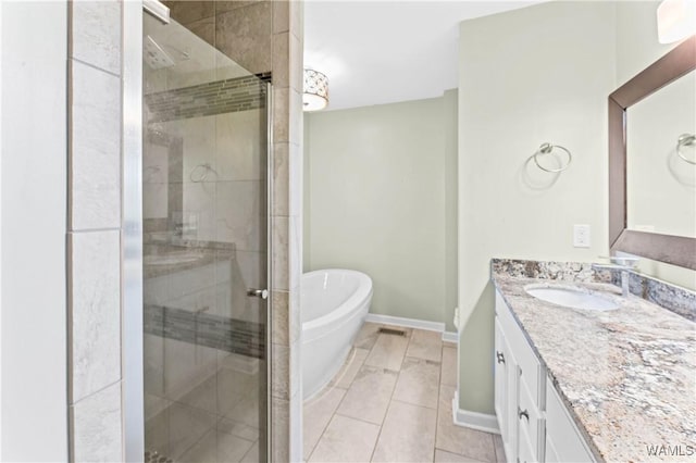 full bathroom featuring vanity, a shower stall, a freestanding tub, and baseboards