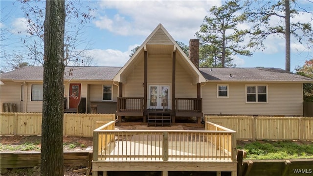 rear view of property featuring french doors, a wooden deck, a fenced backyard, and a shingled roof