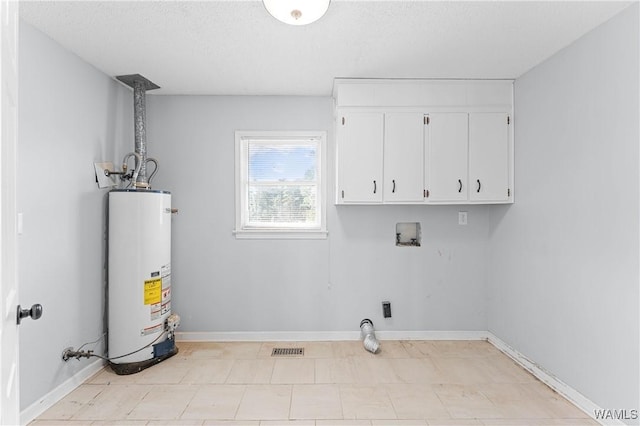 laundry area with baseboards, visible vents, cabinet space, washer hookup, and gas water heater