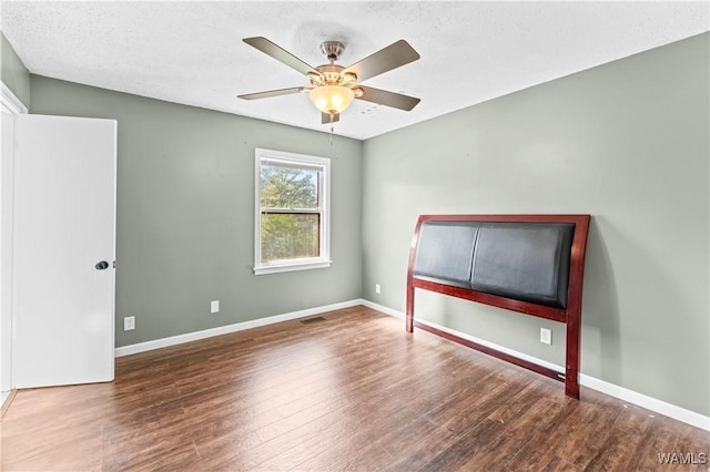 unfurnished bedroom with a ceiling fan, visible vents, wood finished floors, and baseboards