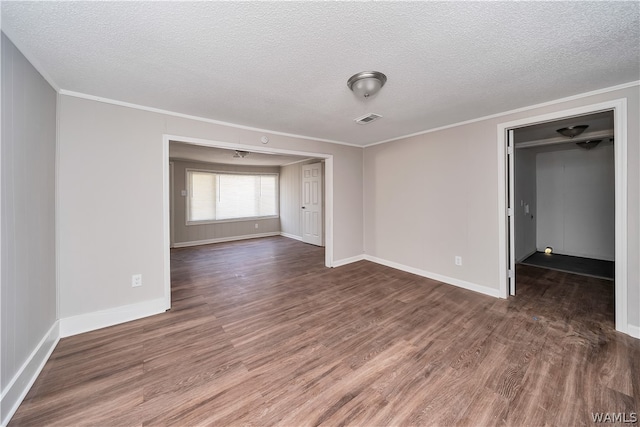 empty room featuring dark hardwood / wood-style floors, crown molding, and a textured ceiling