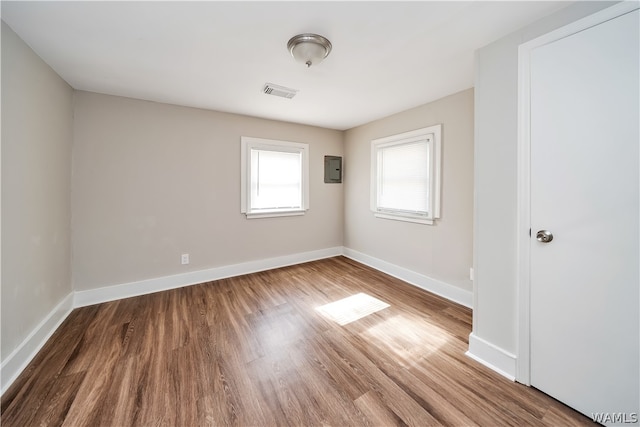 unfurnished room featuring electric panel and hardwood / wood-style floors