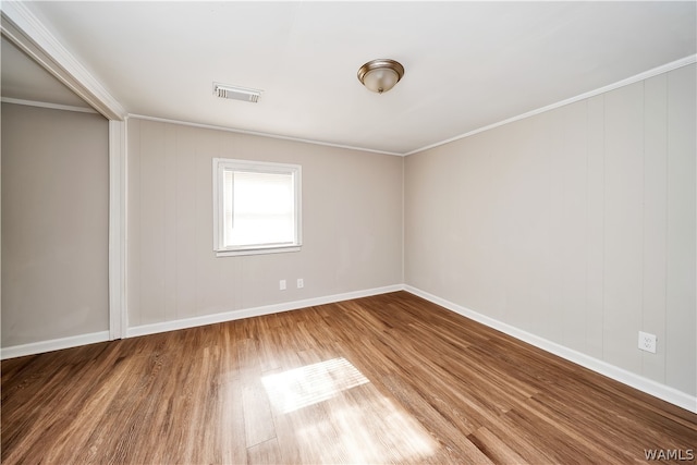 empty room with crown molding and hardwood / wood-style floors