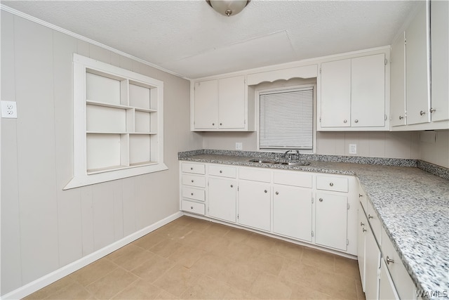 kitchen featuring a textured ceiling, white cabinetry, crown molding, and sink