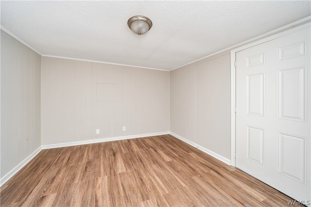 interior space featuring a textured ceiling, light hardwood / wood-style flooring, and ornamental molding