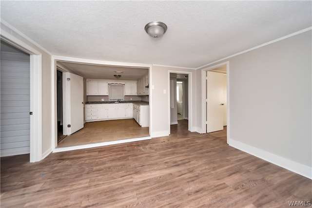 unfurnished living room featuring a textured ceiling, dark hardwood / wood-style floors, crown molding, and sink