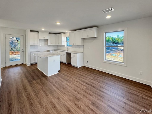 kitchen featuring backsplash, sink, white cabinets, dark hardwood / wood-style floors, and a kitchen island