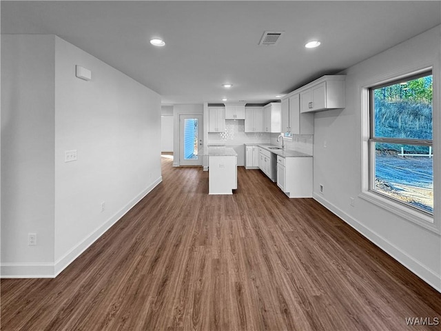 kitchen featuring white cabinetry, a center island, sink, dark wood-type flooring, and tasteful backsplash