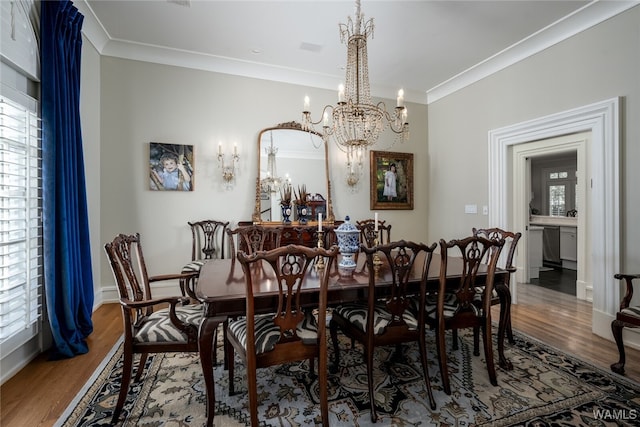 dining room with a chandelier, ornamental molding, and hardwood / wood-style flooring