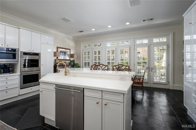 kitchen with a kitchen island with sink, sink, crown molding, white cabinetry, and stainless steel appliances