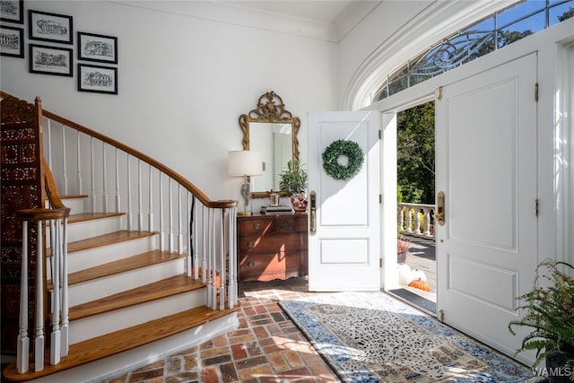 entrance foyer featuring a towering ceiling, plenty of natural light, and ornamental molding