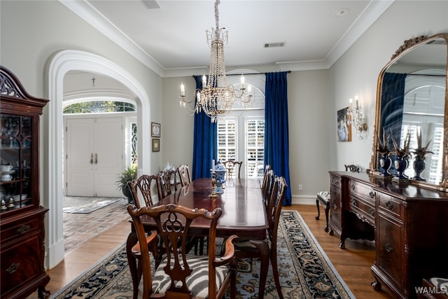 dining room featuring wood-type flooring, ornamental molding, and a chandelier