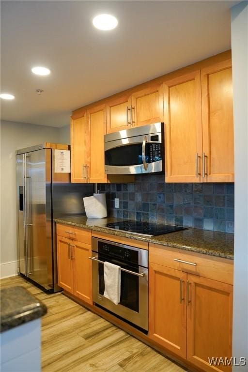 1018 Hackberry Ln Unit 113, Tuscaloosa, AL 35401 - kitchen featuring stainless steel appliances, light wood-style flooring, tasteful backsplash, dark stone counters, and recessed lighting