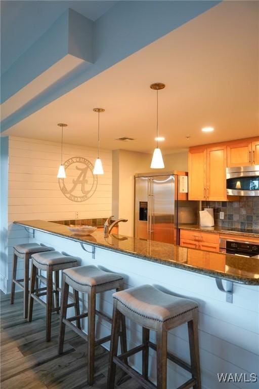 1018 Hackberry Ln Unit 113, Tuscaloosa, AL 35401 - kitchen featuring appliances with stainless steel finishes, a breakfast bar area, decorative backsplash, dark stone counters, and hanging light fixtures