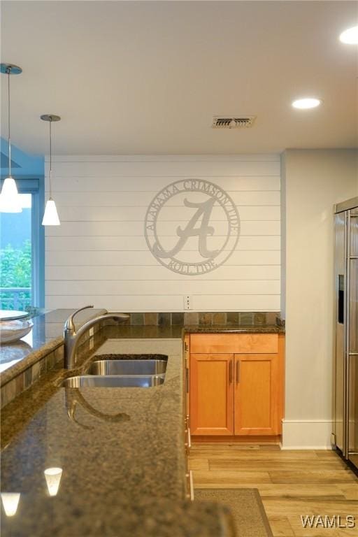 1018 Hackberry Ln Unit 113, Tuscaloosa, AL 35401 - kitchen with light wood-type flooring, dark stone countertops, pendant lighting, recessed lighting, and brown cabinets