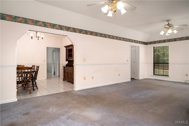 unfurnished living room with light carpet, ceiling fan with notable chandelier, and vaulted ceiling