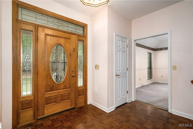 foyer with a textured ceiling, dark parquet floors, and a healthy amount of sunlight