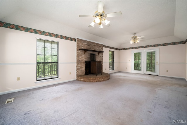 unfurnished living room featuring carpet, ceiling fan, a wood stove, and vaulted ceiling